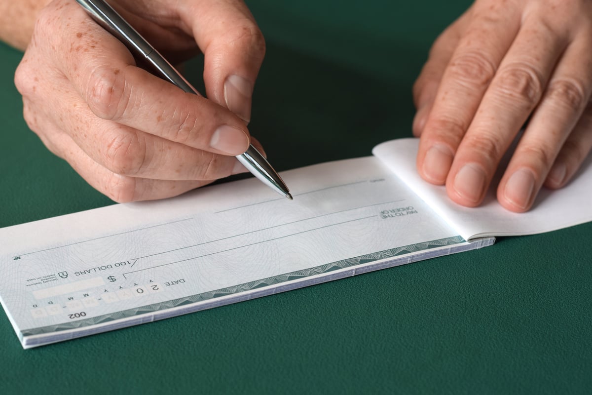 Closeup woman's hands writing bank cheque